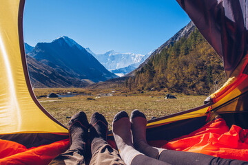 Two people lying in tent with a view of mountains. Belukha Mountain view from the tent in Akkem lake valley. Altai picturesque valley view.