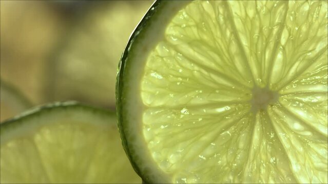 Drop of Lime Juice flow down the surface of a ripe juicy Lime slice. Slow Motion 4K