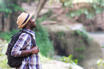African trekking tourist with backpack is thrilled and amazed at the natural beauty of the forest....