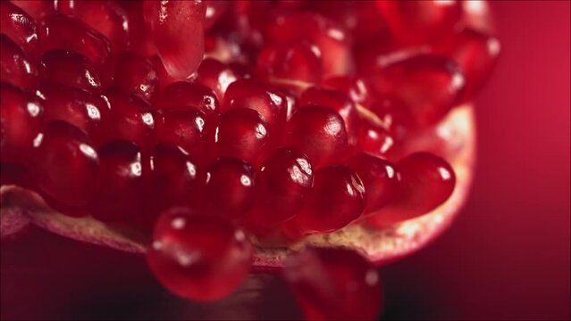 Pomegranate Grains rolls down on surface of broken pomegranate in slow motion