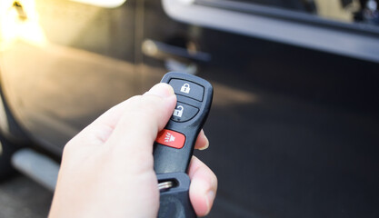 Close up hand of man holding and push car remote control for lock and Un-lock old black car ,Car key and  remote.