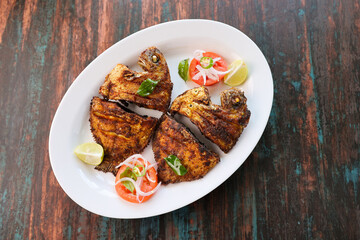 Kerala fish fry Karimeen Pollichathu a popular hot and spicy baked fish in banana leaves Alleppey India. fried pearl spot fish is marinated with Indian spices then grilled or fried in coconut oil.