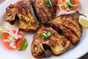 Kerala fish fry Karimeen Pollichathu a popular hot and spicy baked fish in banana leaves Alleppey India. fried pearl spot fish is marinated with Indian spices then grilled or fried in coconut oil.