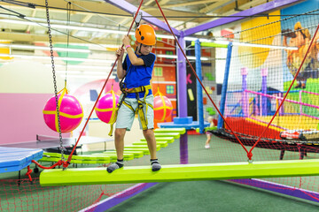 Boy in protective gear holding safety rope and passing obstacle course