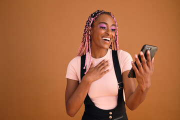 Studio portrait of beautiful young non-conforming with braids on cellphone
 - obrazy, fototapety, plakaty
