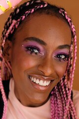 Studio portrait of young  beautiful non-conforming with braids smiling
