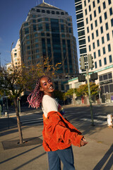 Fototapeta premium Portrait of young non-conforming with braids smiling in the city