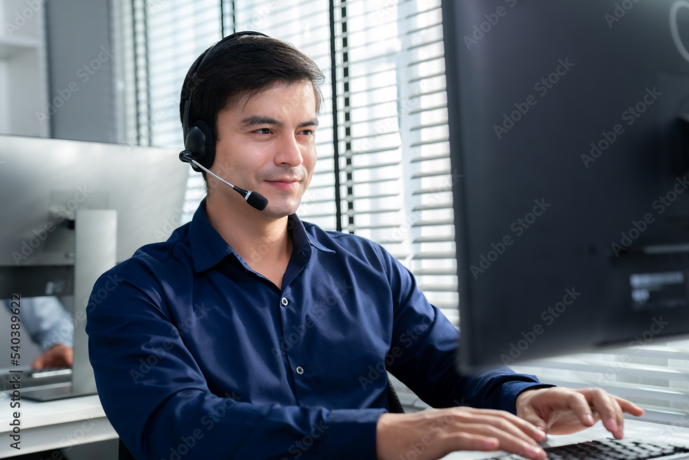 Aufkleber young competent asian male call center agent working at his computer while simultaneously speaking w