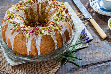Fragrant Persian love cake decorated with with vanilla icing, crushed pistachio nuts and dried rose petals
