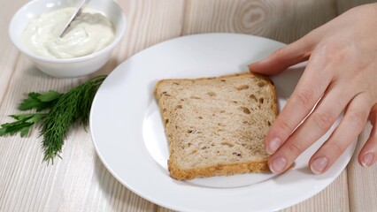 close-up - woman spreads cream cheese on bread - makes a toast