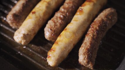 delicious grilled pork sausages rollin on hot grill pan from overhead in 4K