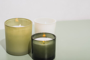 Fototapeta na wymiar green scented candles burning on a table. sow wax candles with herbal aroma glowing in room. aromatherapy, cosy home, grass fragrance for house.