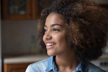 Close up shot beautiful African curly-haired adolescent teen age girl smiling staring into distance...