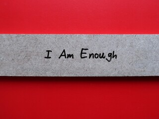 Piece of wood on red background with handwritten text I Am Enough - Positive self talk affirmation...