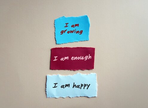Torn paper note with handwritten text I AM GROWING I AM ENOUGH I AM HAPPY - positive affirmations self talk practice for daily encouragement and boost self esteem or self worth