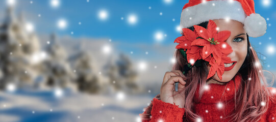 happy young girl with poinsettia flower and santa claus hat on snowy background at christmas