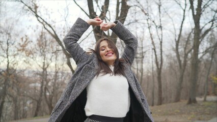 A girl in a coat is dancing on the street. Outdoors lifestyle fashion portrait of a happy stunning brunette girl. Dancing on a city street. Go shopping. Wearing a stylish coat. Happiness concept