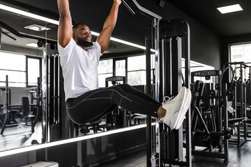 Strong african man doing statics exercise on horizontal bar, having workout at gym.