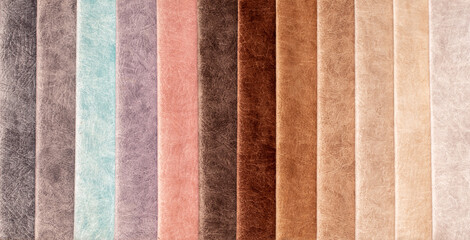Fototapeta premium Fabric texture close up. Fabric swatches in different colors are stacked for selection. A variety of shades of upholstery material for furniture and interior. A set of multi-colored rolls of material.
