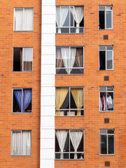 Building facade with many windows and curtains. The building is made of bricks. Beautiful geometric composition, Bogota, Colombia.