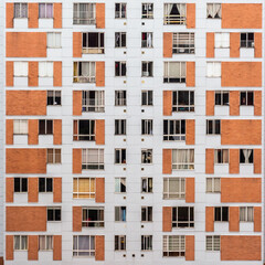 Fototapeta na wymiar Building facade with many windows and curtains. The building is made of bricks. Beautiful geometric composition, Bogota, Colombia.