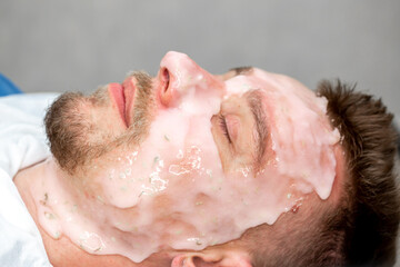 A man at a beautician's appointment. Treatments for men, face cleansing, skin peeling, moisturizing nourishing facial mask. Male spa salon.