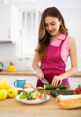Obraz na płótnie Canvas Smiling woman cooking dinner at home