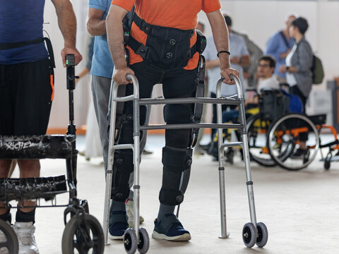 Boy with Mobility Problems in Lower Limbs in Upright Posture Walking Thanks to a Mechanical Exoskeleton and with the Help of his Physical Therapist