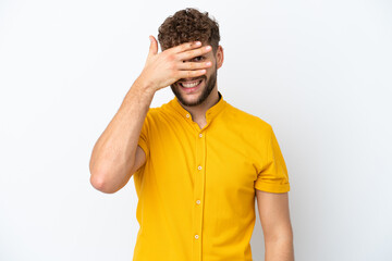 Young handsome caucasian man isolated on white background covering eyes by hands and smiling