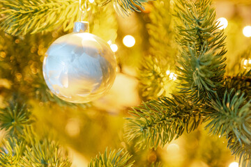 a white Christmas bauble on a Christmas tree, close-up