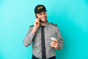 Young security man isolated on blue background holding coffee to take away and a mobile