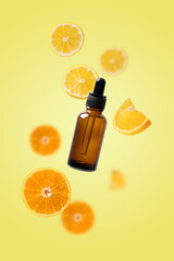 Citrus fruits and dark glass cosmetic bottle falling in the air. Beauty serum with lemons and oranges isolated on yellow background. Cosmetic oil, vitamin C concept