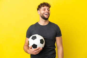 Handsome young football player man isolated on yellow background laughing