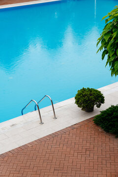 The concept of summer holidays and architecture. Blue swimming pool in the rain.