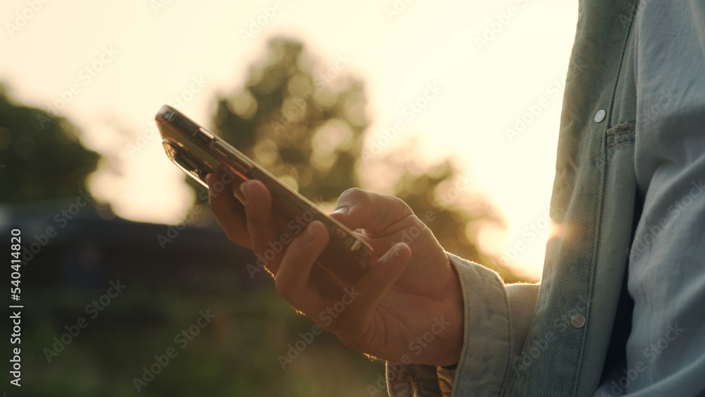 Wall mural hands using mobile over sunset. close-up of men's hands with a mobile in their hands typing sms. per