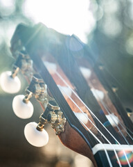 Close-up of the guitar head of a classical guitar with gold pegs. Part of a classical guitar on a...