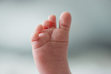 Close-up of a newborn baby's foot. Close-up of baby toes of a newborn baby. The little leg of a white baby.  Tiny child's foot, rear view. Healthy and clean skin of a little child foot.