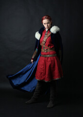  portrait of beautiful woman wearing a red medieval fantasy warrior costume with leather armour.  Standing pose isolated on studio background.