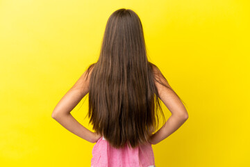 Little caucasian girl isolated on yellow background in back position