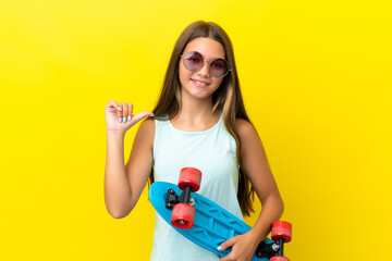 Little caucasian skater girl isolated on yellow background with a skate with happy expression