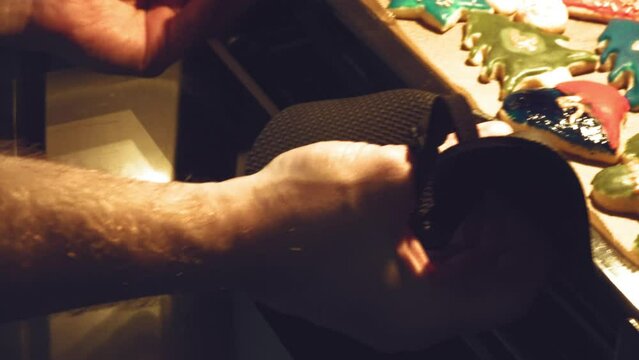 frisch gebackene Pl&auml;tzchen werden aus dem Backofen geholt	