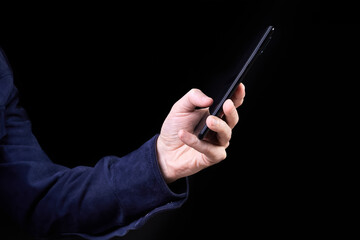 Man presses his finger on the screen of a smartphone on a dark background