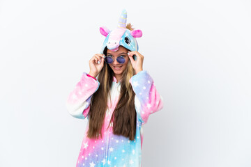 Little caucasian girl wearing unicorn pajama isolated on white background with glasses and surprised