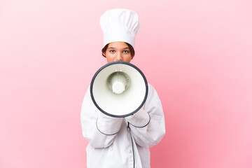 Little caucasian chef girl isolated on pink background shouting through a megaphone