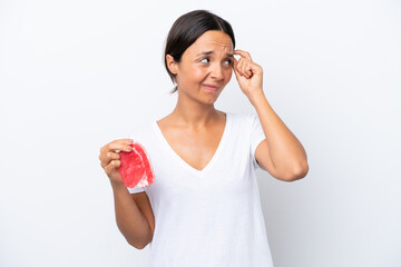 Young hispanic woman holding a piece of meat isolated on white background having doubts and with confuse face expression