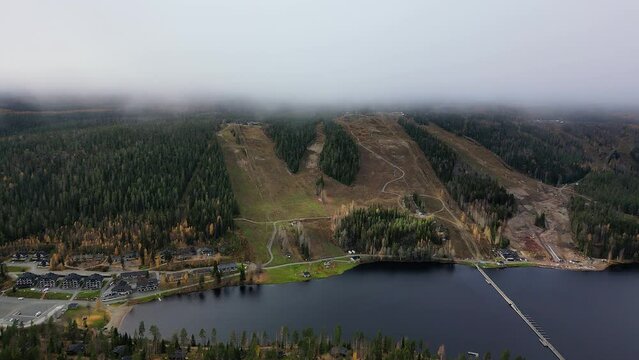 Aerial footage of Tahko mountain ski resort in Kuopio, Finland. Autumn season with lots of fog on mountain peak level. Narrow bridge crossing the Tahkolahti bay.