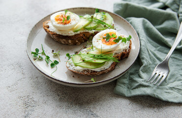 Bread toast, boiled eggs, avocado slice, microgreens on a plate