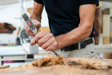 Schreiner meister arbeitet mit Hammer und Meißel an einem Holzstück close up Foto