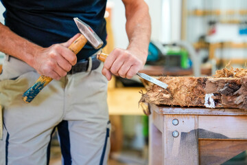 Schreiner meister arbeitet mit Hammer und Meißel an einem Holzstück close up Foto