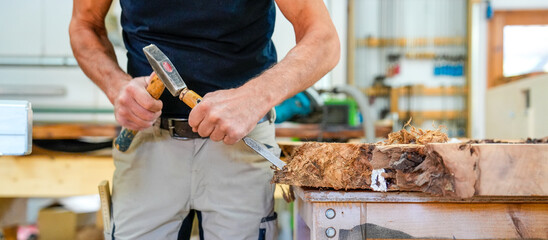 Schreiner meister arbeitet mit Hammer und Meißel an einem Holzstück close up Foto
